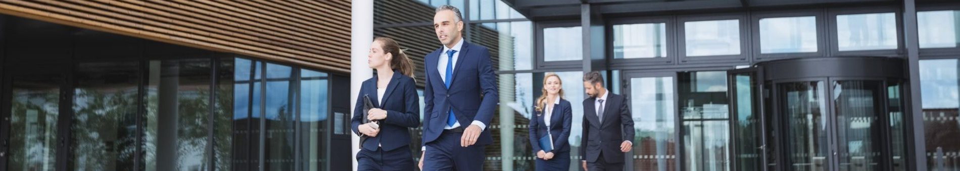 Group of business people walking outside the entrance of an office building